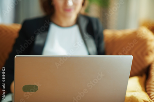 modern female using website on laptop while sitting on couch