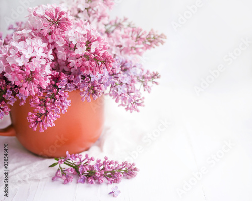 Bouquet of lilacs in a vase on a table on a white background  copy space  soft focus 