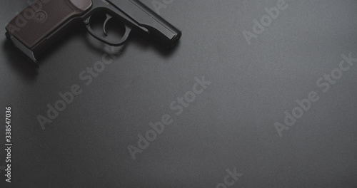 gun on a black background and falling a bundle of dollars in left side