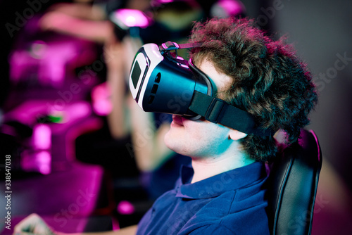 Side view of positive young curly-haired gamer playing videogame in virtual reality goggles © pressmaster