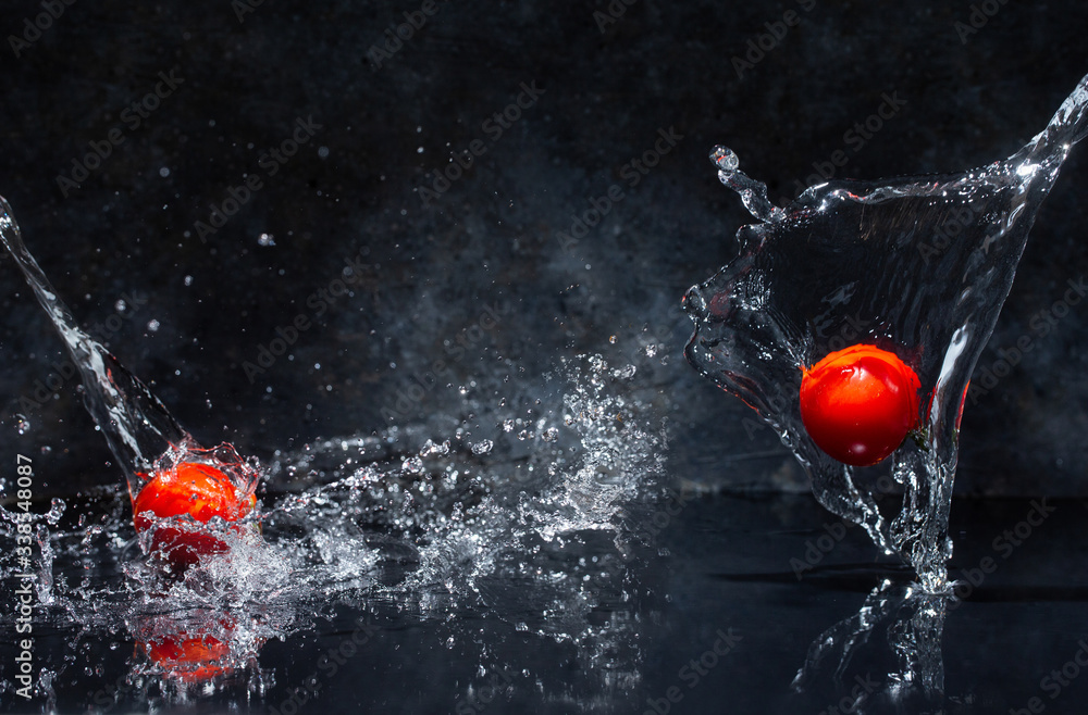flying red tomatoes in water drops on a gray background