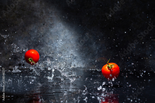flying red tomatoes in water drops on a gray background
