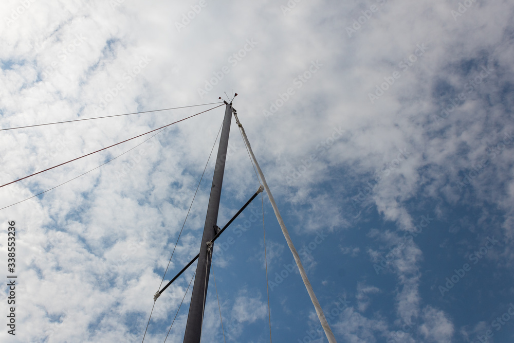 Sailing ship mast and rigging against a blue sky with clouds, horizontal aspect Sailing ship mast and rigging against a blue sky with clouds, horizontal aspect