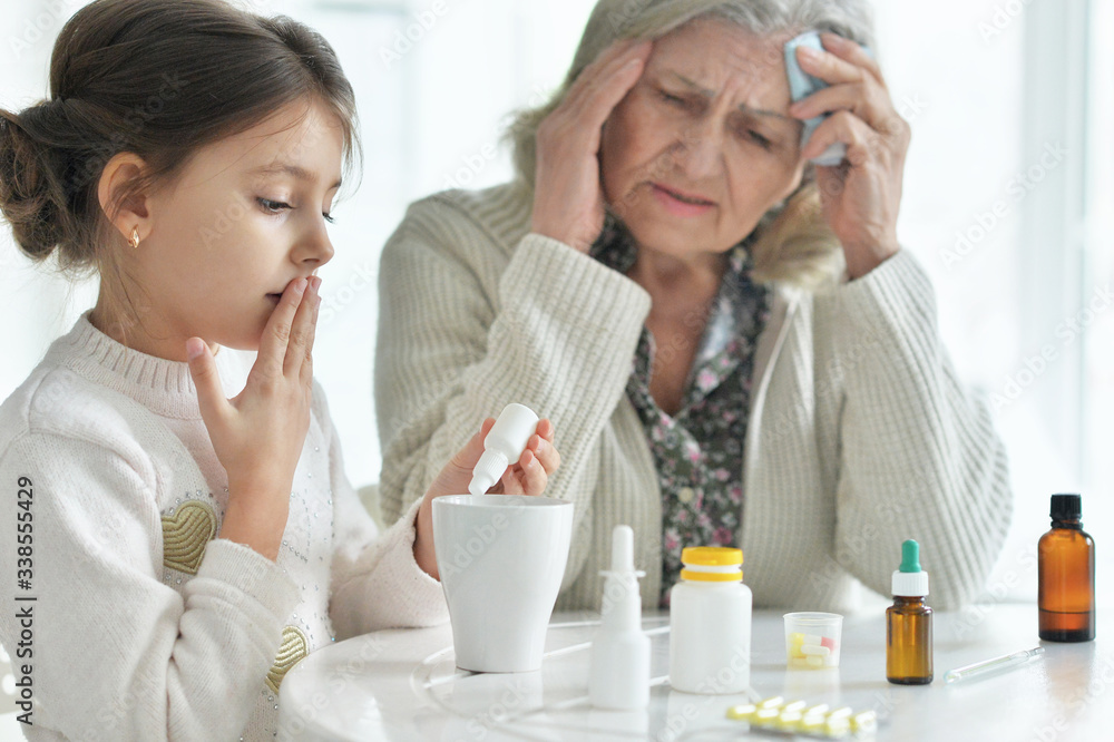 Cute girl giving medicine to sick senior woman Cute girl giving medicine to sick senior woman
