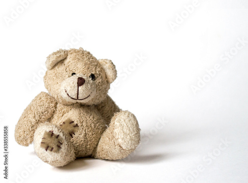 a cute and ridiculous baby soft toy teddy-bear sitting on a bright background