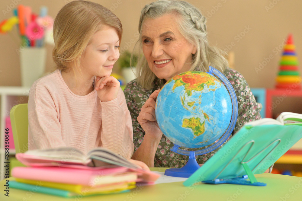 Close up portrait of grandmother with cute little girl doing homework Close up portrait of grandmother with cute little girl doing homework