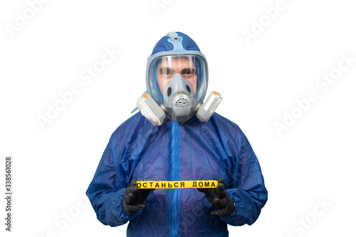 Obraz na płótnie a man in a protective blue suit and a protective mask holds a sign stay at home w salonie