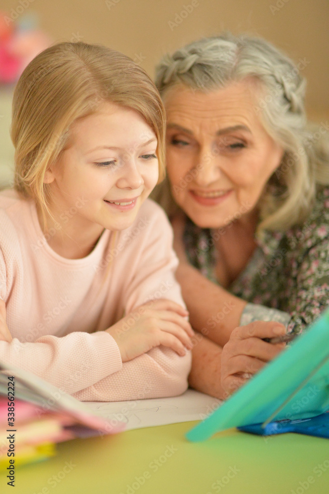 Close up portrait of grandmother with cute little girl doing homework Close up portrait of grandmother with cute little girl doing homework
