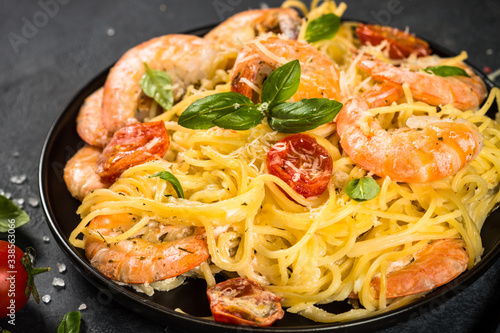 Pasta seafood with shrimp on black table.