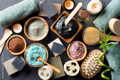Spa. Natural cosmetics for the body and face. Blue sea salt with seaweed, soaps of herbs and dead sea mud, loofah washcloth, massage brush, ground coffee scrub on a dark table. Top view.