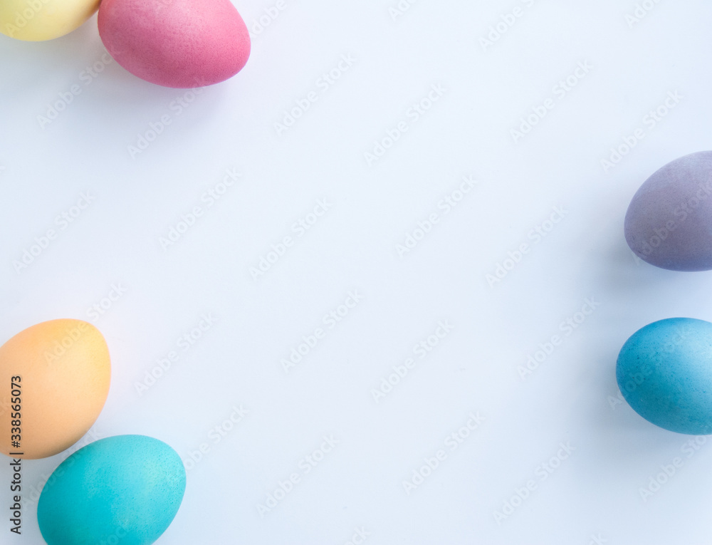 Colourful easter eggs in the corners, copy space. Eggs are painted in yellow, pink, blue, orange and purple. White background