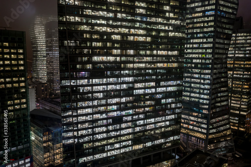 Aerial drone night shot of people working in offices in skyscrrapers in La defense, Financial district in Paris
