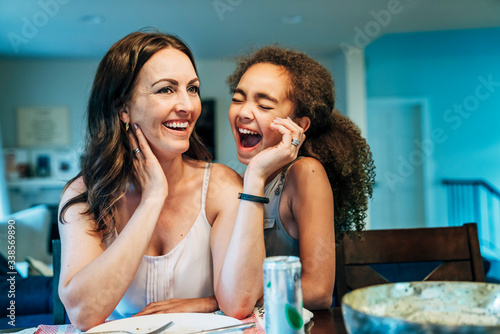 Mom and daughter sitting at kitchen table laughing