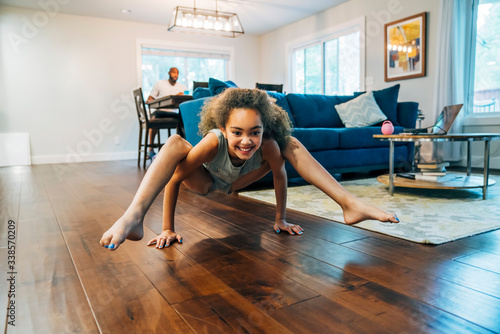Smiling girl doing crab crawl on living room floor