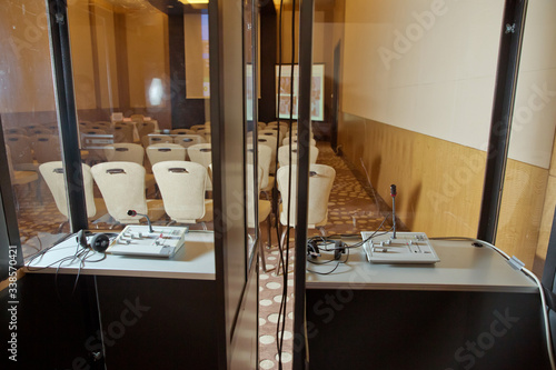 Soft focus of wireless Conference microphones and notebook in a meeting room. translators cubicle . interpreting - Microphone and switchboard in an simultaneous interpreter booth . photo