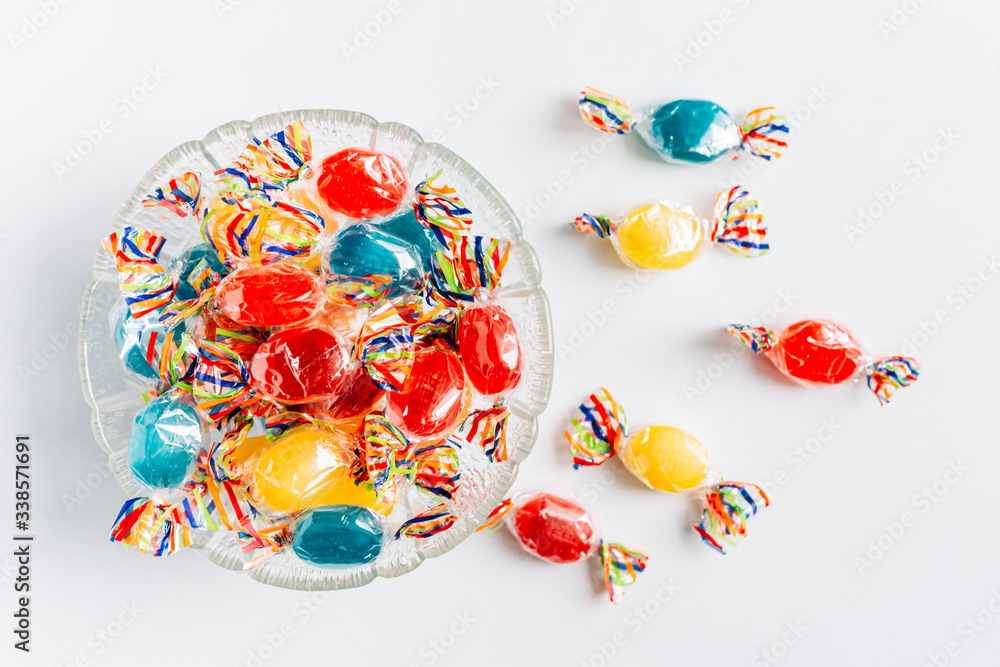 Bowl full with mix hard wrapped candies isolated on white background.