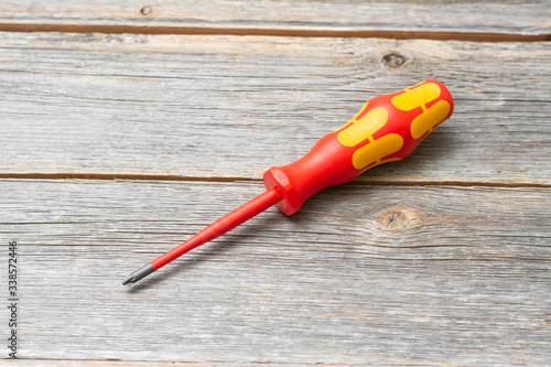 A dielectric screwdriver for an electrical fitter on a gray table. Screwdriver for electrical work