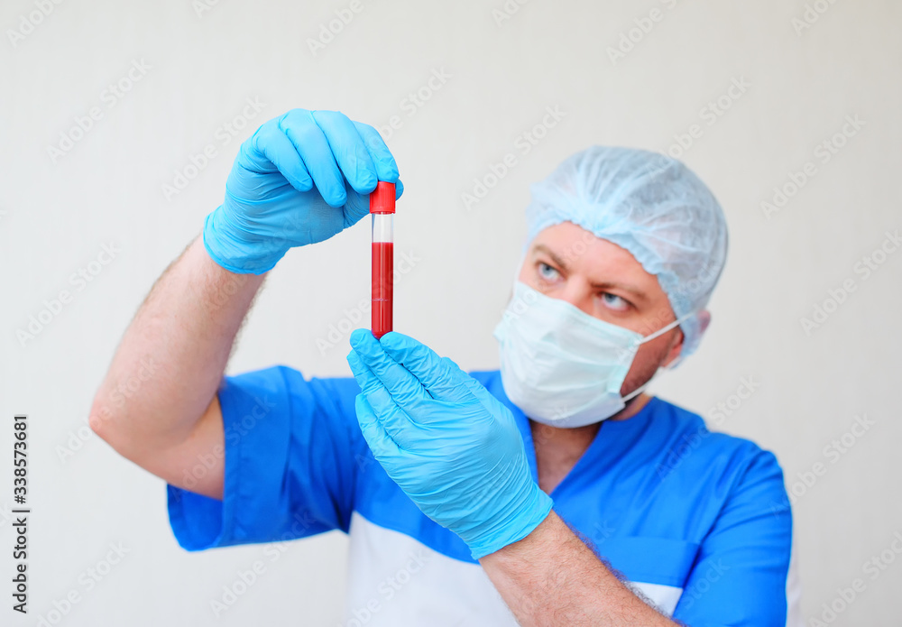 a test tube with a blood sample in the hands of a doctor in blue rubber gloves and a mask on a light background. Concept of coronavirus, covid-19 a test tube with a blood sample in the hands of a doctor in blue rubber gloves and a mask on a light background. Concept of coronavirus, covid-19