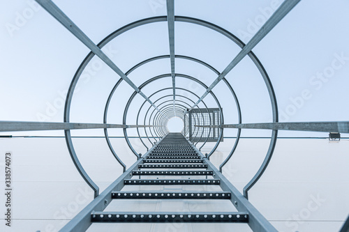 Outdoor fire escape ladder on wall of building in perspective seen from below