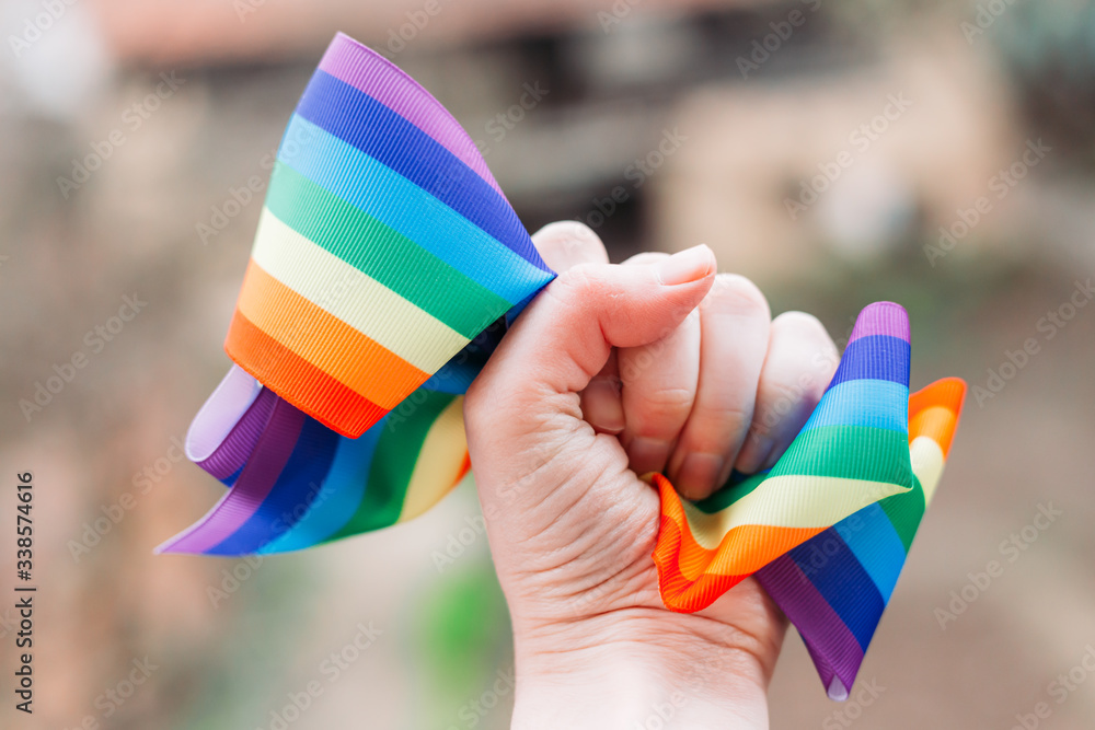 Female hand holding textile rainbow fabric tightly. Symbol of fight for rights Female hand holding textile rainbow fabric tightly. Symbol of fight for rights