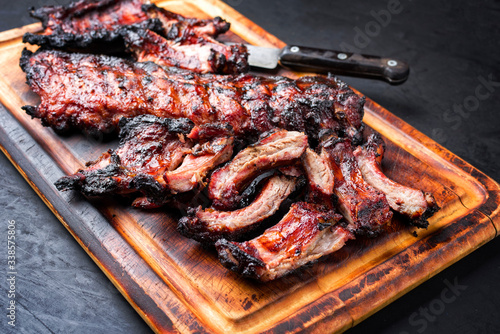Barbecue pork spare loin ribs St Louis cut with hot honey chili marinade sliced and burnt as closeup on a wooden cutting board