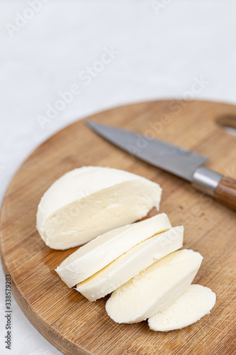 Sliced Mozarella cheese on the round wooden board