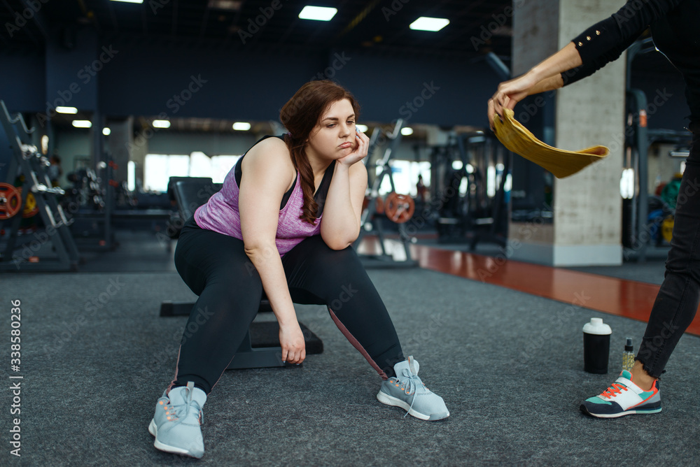 Tired overweight woman with trainer in sport club Tired overweight woman with trainer in sport club