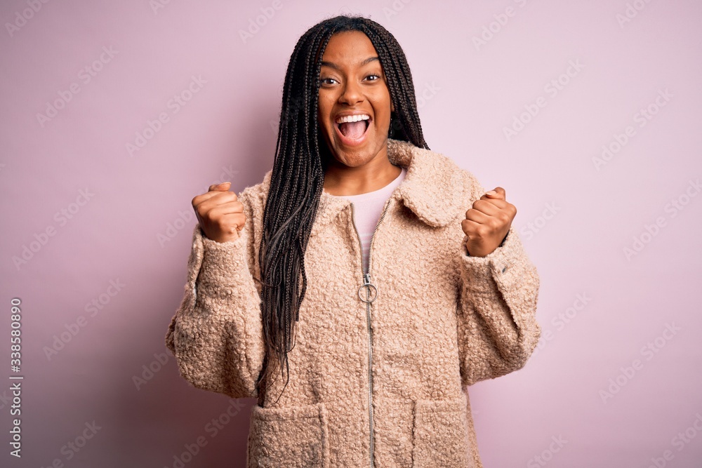 Young african american woman wearing fashion winter coat over pink isolated background celebrating surprised and amazed for success with arms raised and open eyes. Winner concept.