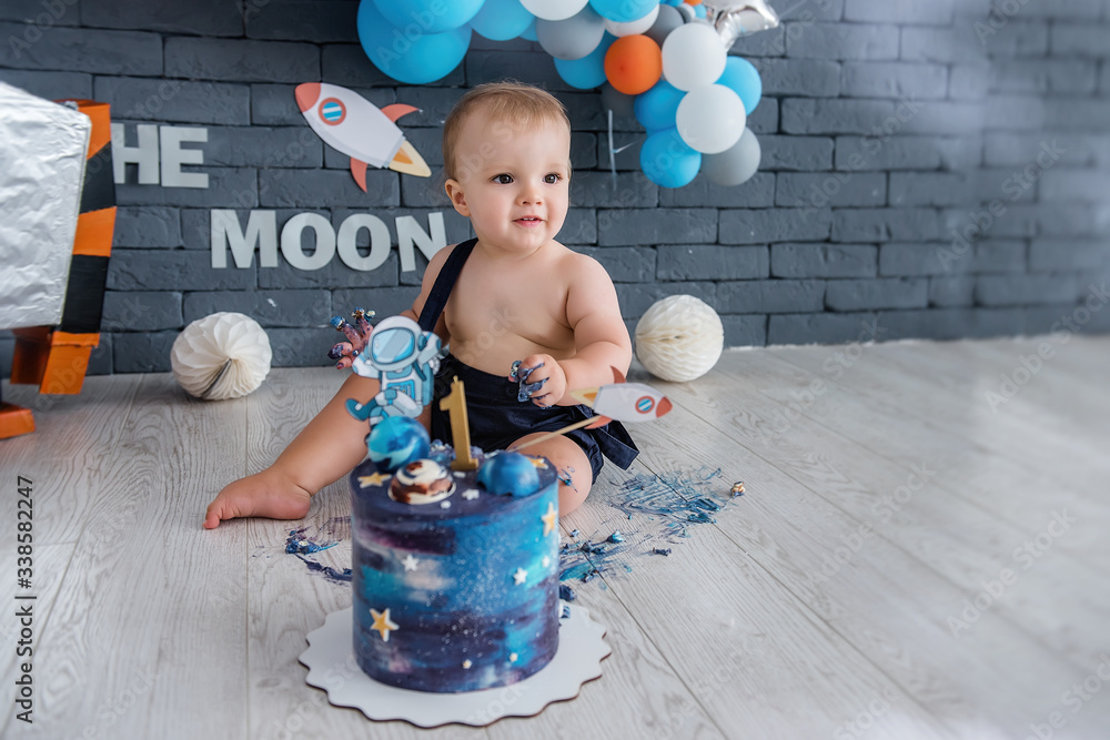 Fototapeta premium Little boy celebrates his first birthday. Space design with a robot and stars, many colorful balloons.