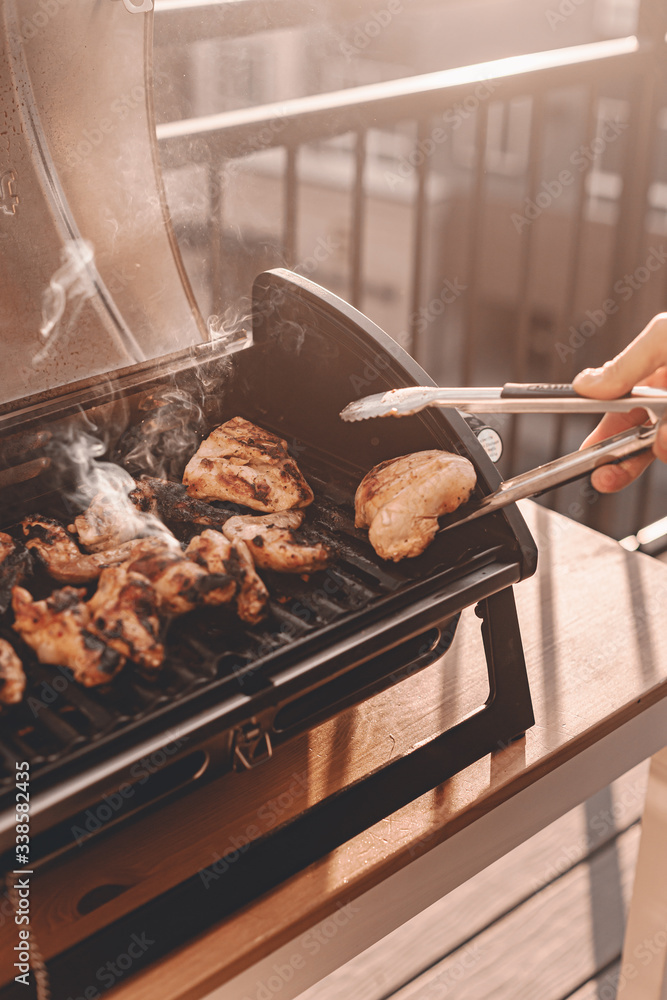 Grill season outdoor in park or balcony. Spring summer grilling. Balcony  gas grill. Barbeque fourth of July weekend. Chicken wings on grill. Flame  and smoke over grill. BBQ quarantine on balcony. Stock