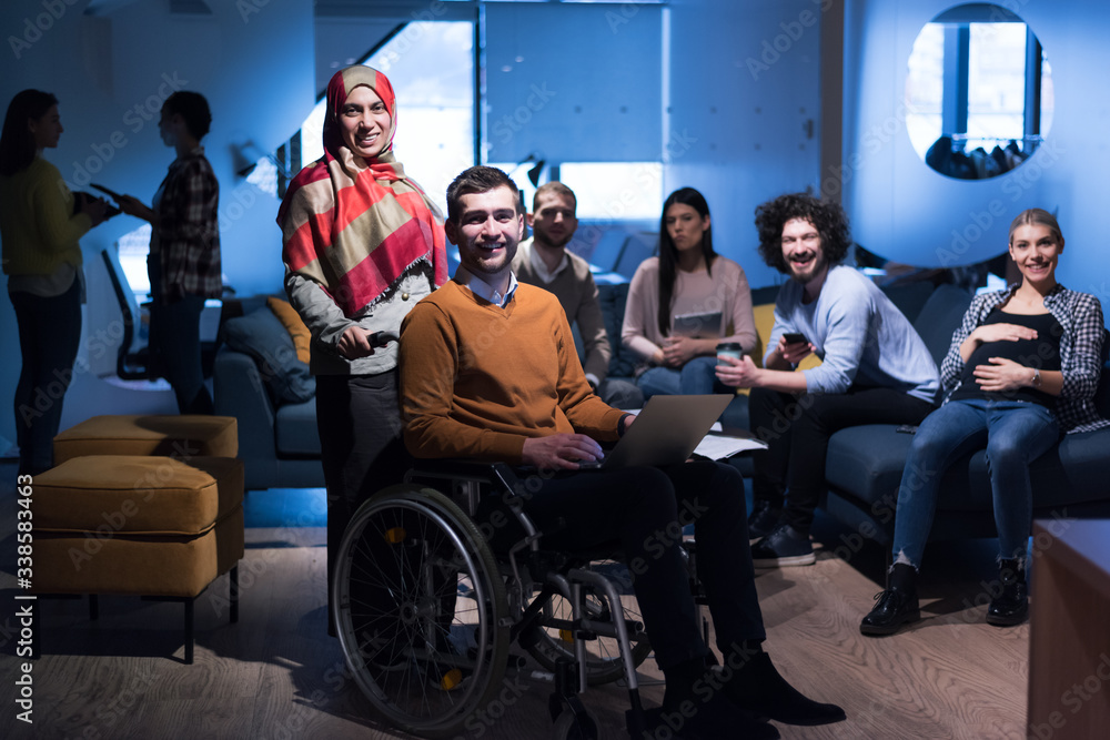 Handicapped young man with colleagues working in office. Office people working together. Looking into camera Handicapped young man with colleagues working in office. Office people working together. Looking into camera