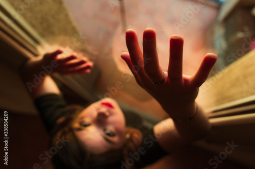 Hand of a young woman on the glass of a window