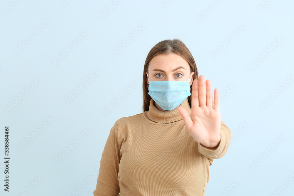 Woman in protective mask showing stop gesture on color background. Concept of epidemic Woman in protective mask showing stop gesture on color background. Concept of epidemic