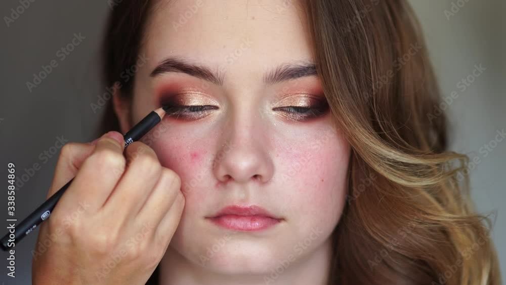 Girl makeup artist paints the eyes of a young girl Girl makeup artist paints the eyes of a young girl