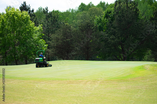 A lawn mower maintaining a green on a golf course
