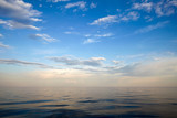 Serene, calm lake. Gentle blue sky with white clouds.