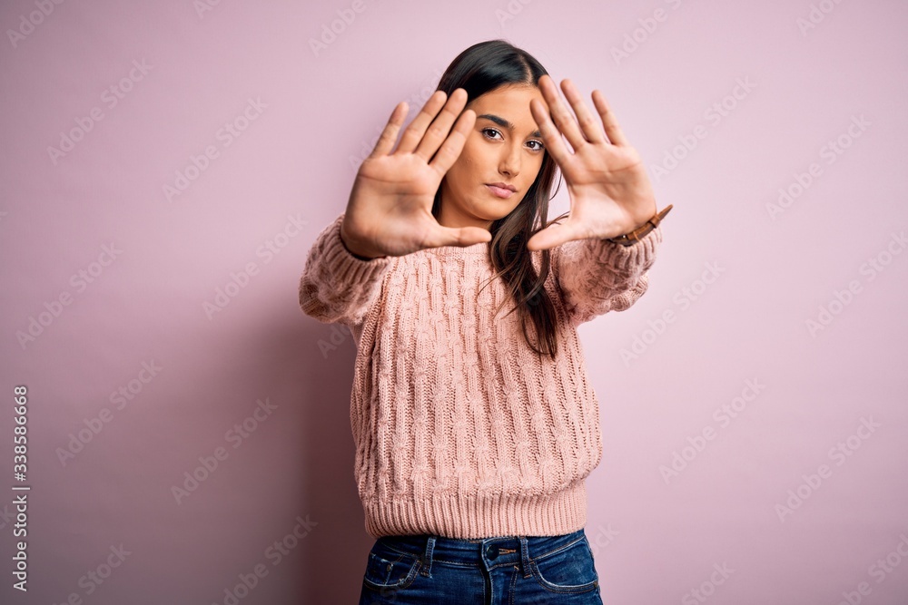 Young beautiful brunette woman wearing casual sweater over isolated pink background doing frame using hands palms and fingers, camera perspective Young beautiful brunette woman wearing casual sweater over isolated pink background doing frame using hands palms and fingers, camera perspective