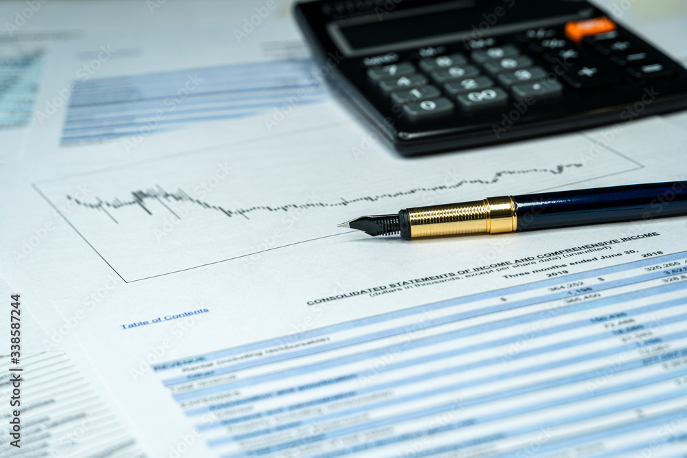 Analyzing finance report with calculator and pen. Investment report in crisis time Analyzing finance report with calculator and pen. Investment report in crisis time