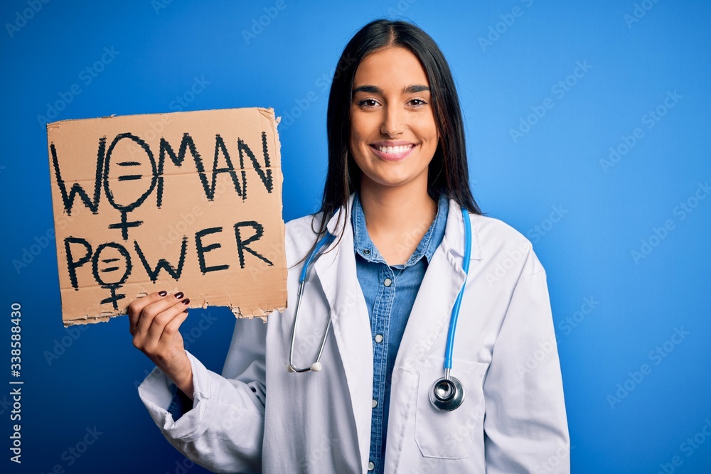Young doctor woman wearing stethoscope holding cardboard banner with powe message with a happy face standing and smiling with a confident smile showing teeth Young doctor woman wearing stethoscope holding cardboard banner with powe message with a happy face standing and smiling with a confident smile showing teeth
