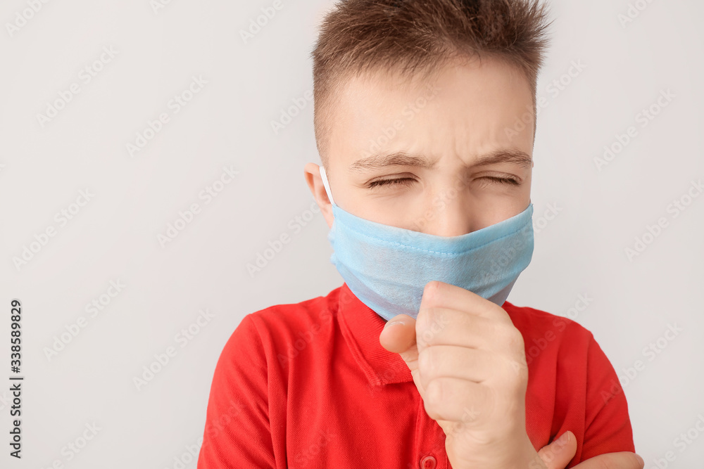 Ill little boy wearing protective mask on grey background. Concept of epidemic Ill little boy wearing protective mask on grey background. Concept of epidemic