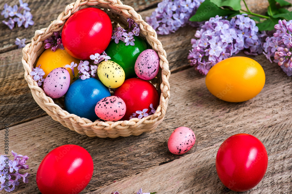 Natural dye colored easter eggs in a basket and lilac flowers on rustic wooden table Natural dye colored easter eggs in a basket and lilac flowers on rustic wooden table