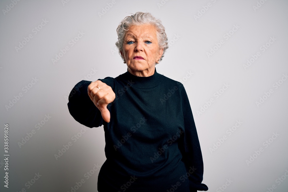 Senior beautiful woman wearing casual black sweater standing over isolated white background looking unhappy and angry showing rejection and negative with thumbs down gesture. Bad expression.