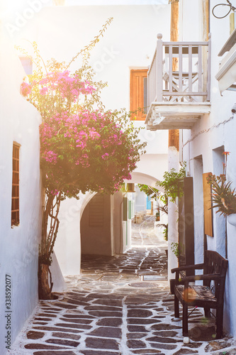 Picturesque narrow street with traditional whitewashed houses with blooming bougainvillea flowers of Naousa town in famous tourist attraction Paros island, Greece
