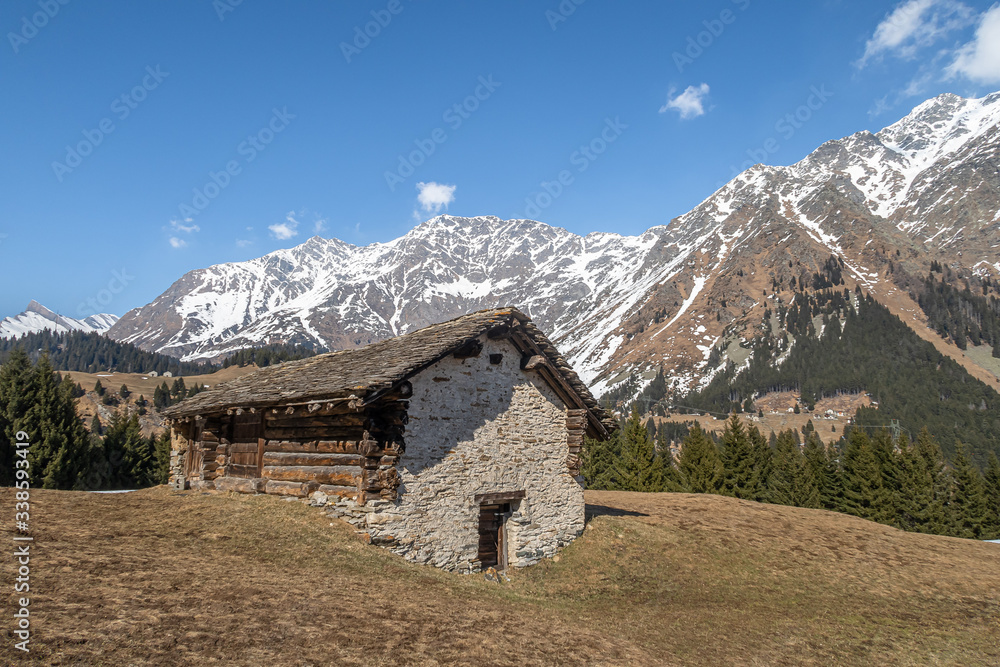 SAN BERNARDINO, SWITZERLAND - APRIL 2, 2020: A shepherd's cottage under the village of San Bernardino, surrounded by the Alps