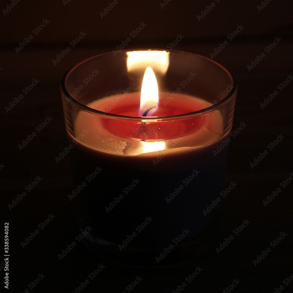red candle burns with a bright flame in a glass candlestick in a dark room, the concept of magic, spiritualism, mourning, commemoration of the dead red candle burns with a bright flame in a glass candlestick in a dark room, the concept of magic, spiritualism, mourning, commemoration of the dead