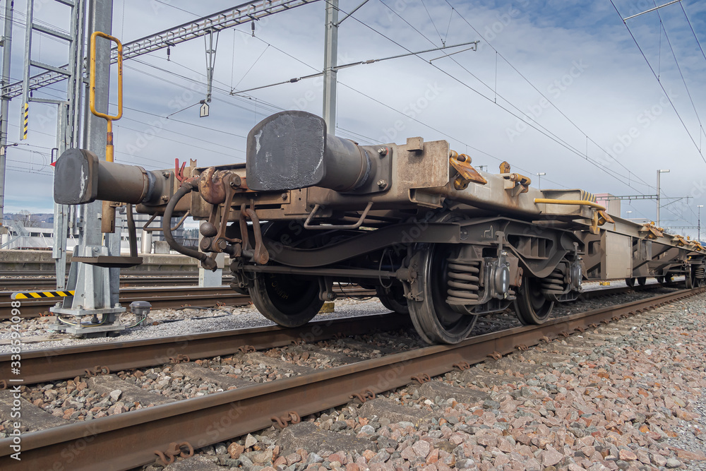 Obraz premium LUPFIG, SWITZERLAND - MARCH 8, 2020: Rusty empty railway chassis-wagon for transporting vehicles on the railway track at Lupfig