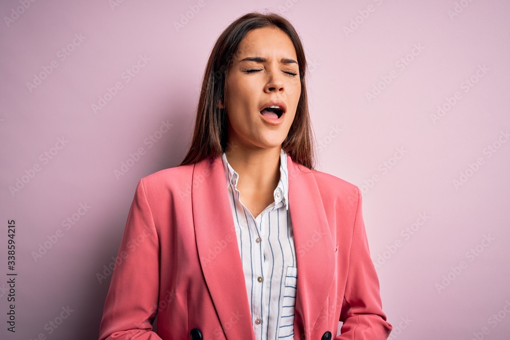 Young beautiful brunette woman wearing jacket standing over isolated pink background with hand on stomach because nausea, painful disease feeling unwell. Ache concept. Young beautiful brunette woman wearing jacket standing over isolated pink background with hand on stomach because nausea, painful disease feeling unwell. Ache concept.