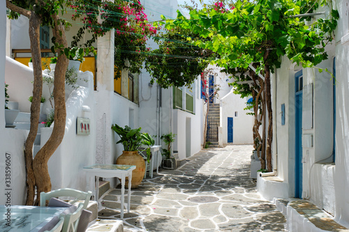 Picturesque narrow street with traditional whitewashed houses with cafe tables of Naousa town in famous tourist attraction Paros island, Greece © Dmitry Rukhlenko