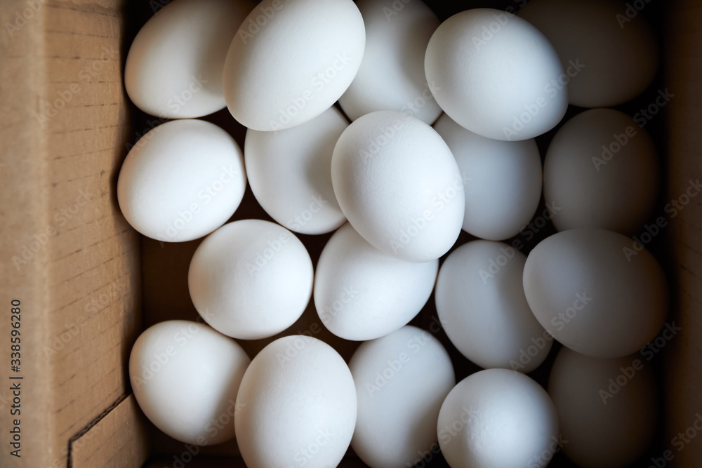 Oval white chicken eggs in a square cardboard box on the top vi Oval white chicken eggs in a square cardboard box on the top vi