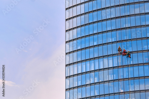Slika na platnu Mens workers in red and dark work clothes cleaning the exterior windows of a bus